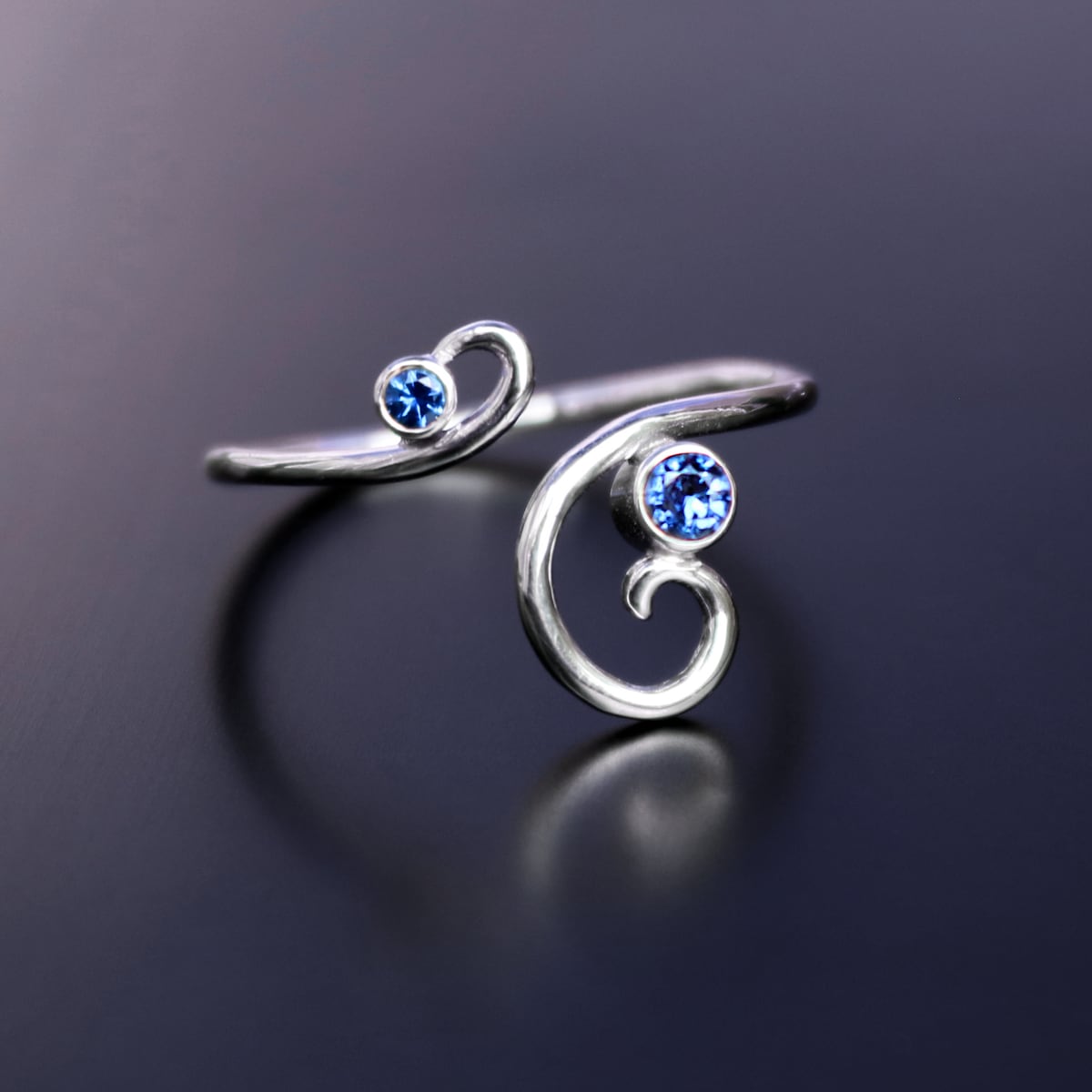 A finished Alumia ring — polished sterling silver set with sapphire-blue stones