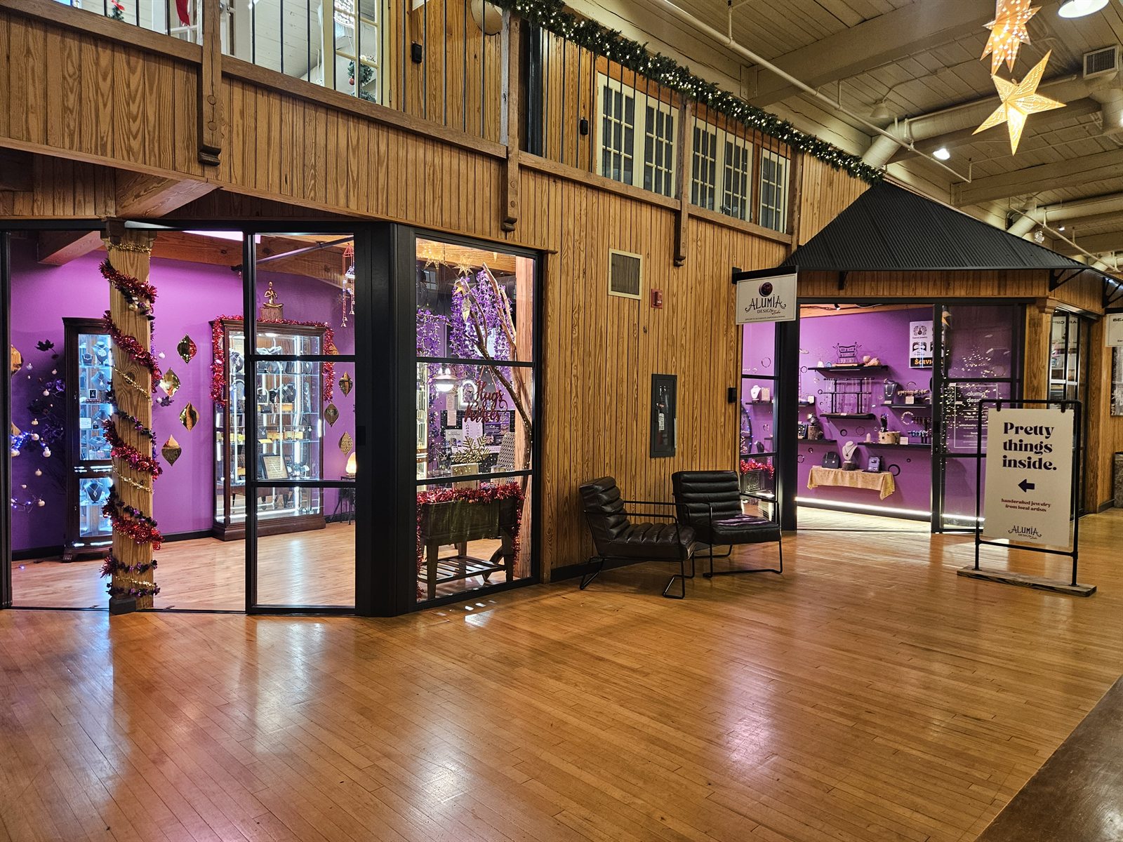 The Alumia Design Studio storefront inside the New Weave Building at Savage Mill — purple-lit windows, the Alumia sign, and the 'Pretty things inside' board